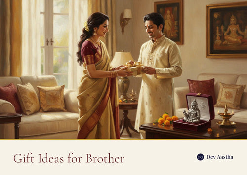 An Indian sister handing a wrapped gift box to her brother in a sunlit living room, a silver-plated Hanuman idol resting in an open velvet gift box beside them with marigolds and a lit diya