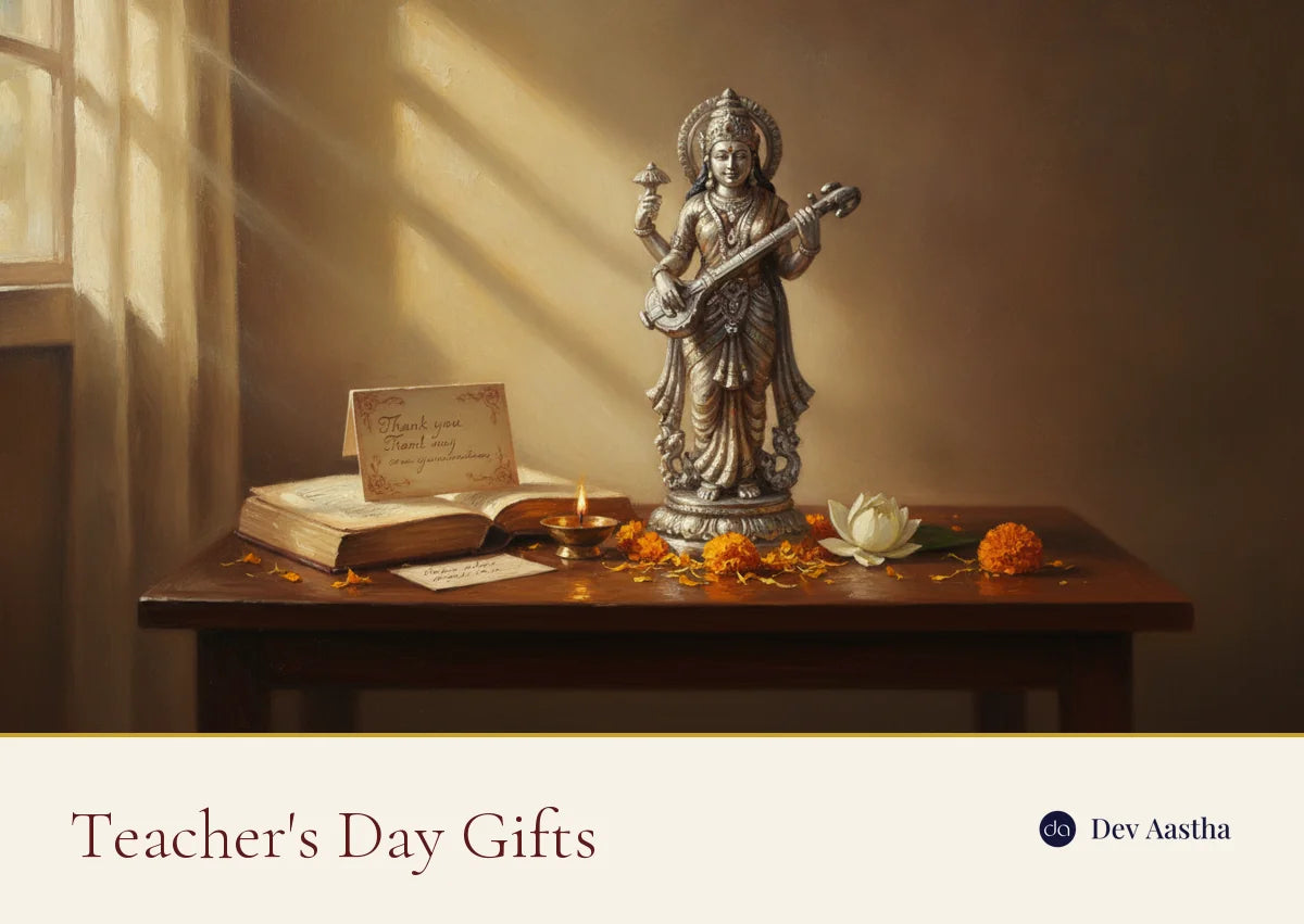 A silver-plated Saraswati idol on a study table as a Teacher's Day gift, with an open book, a lit diya, a handwritten thank-you card and marigolds