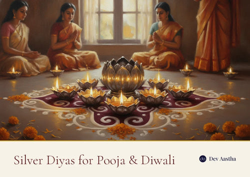Lit silver-plated lotus and flower diyas on a Diwali rangoli with marigold petals