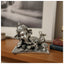 Silver Ganesha idol lying with an open book and a bowl of sweets on a wooden surface