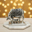 Silver cow and calf figurine with intricate floral engravings on marble base and bokeh background