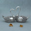 Silver decorative lovebird sculpture with textured bodies and entwined necks forming a heart shape on grey background