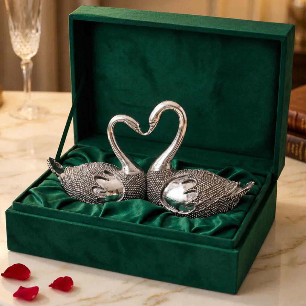 Pair of silver-plated lovebird swans forming a heart in green velvet gift box with rose petals