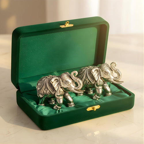 Pair of silver-plated elephant murtis with raised trunks resting in an open green velvet box #common