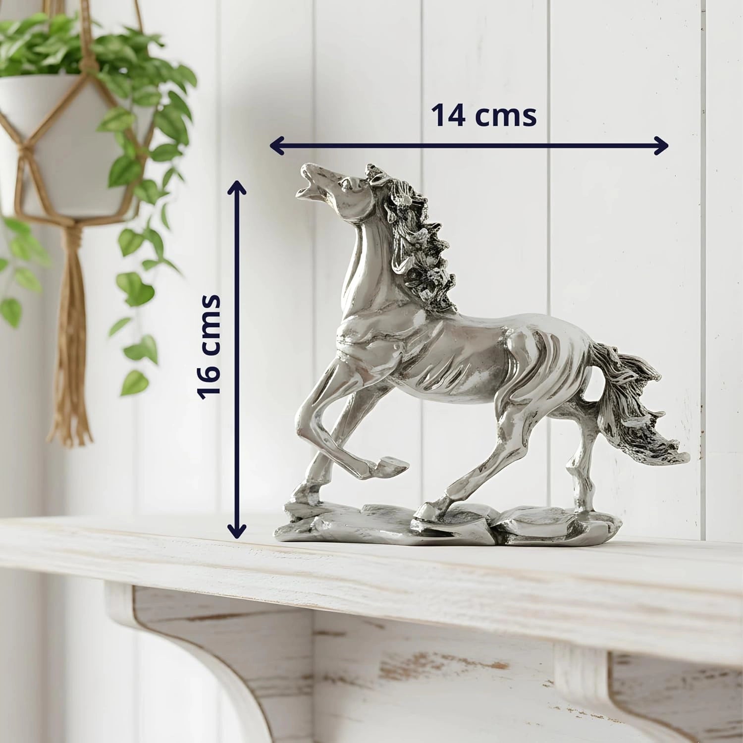 Silver decorative horse statue with raised hooves on a white wooden shelf with plant