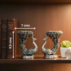Pair of decorative silver peacock bookends on wooden shelf with books and succulent pot