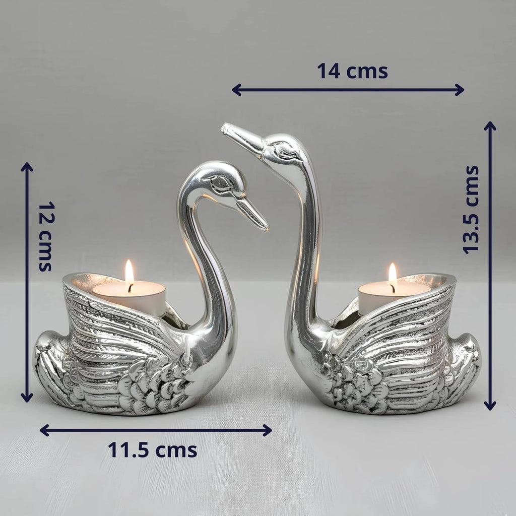 Silver swan-shaped tealight candle holders with detailed wings, each holding a lit candle