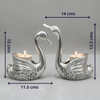 Silver swan-shaped tealight candle holders with detailed wings, each holding a lit candle