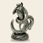 Silver metallic abstract sculpture of snake coiled around a cow's head on textured base