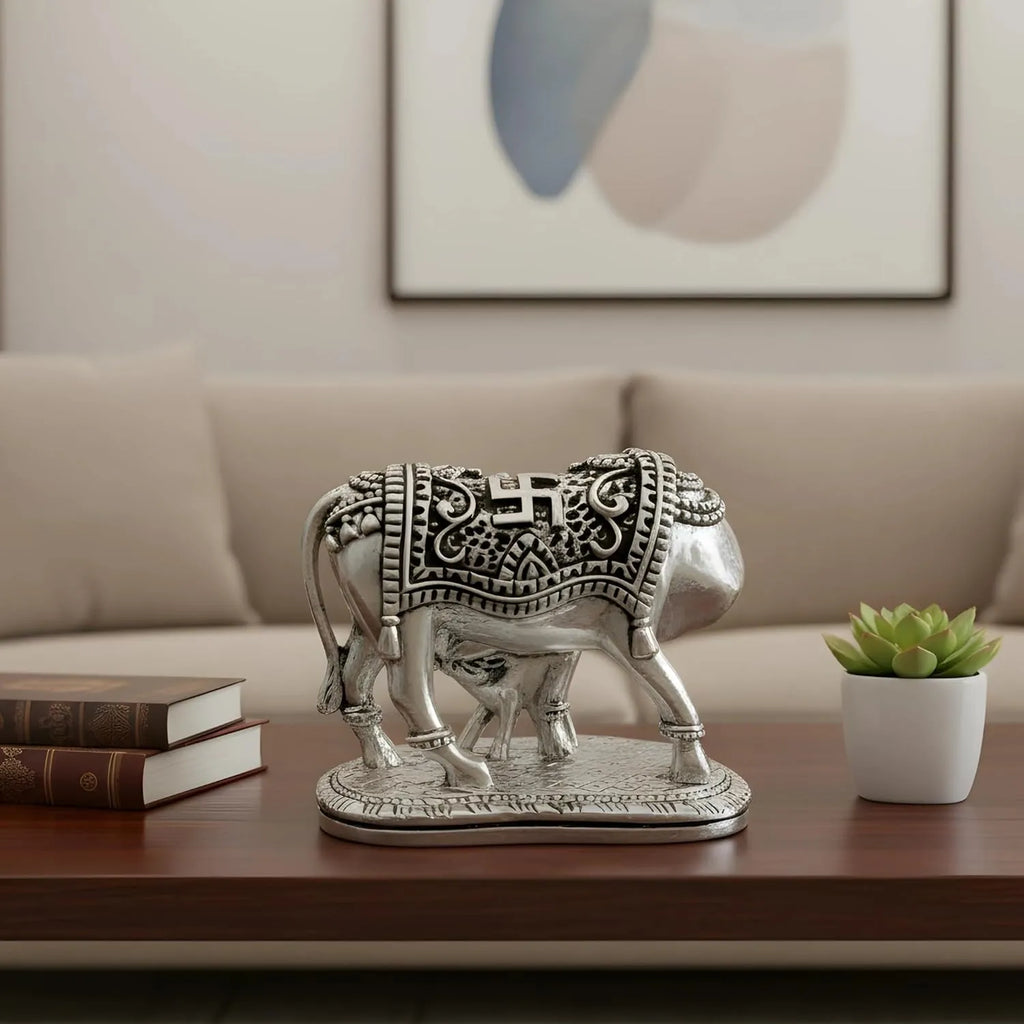 Silver decorative cow statue with intricate designs on wooden table in modern living room