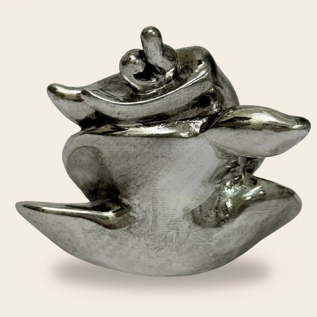 Polished silver abstract sculpture with smooth, curving forms on beige background
