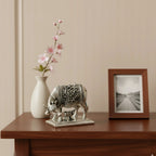 Decorative silver cow and calf statue on wooden table with white vase and photo frame
