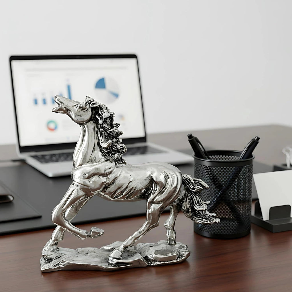 Silver running horse statue on wooden desk with laptop, pen holder, and office supplies