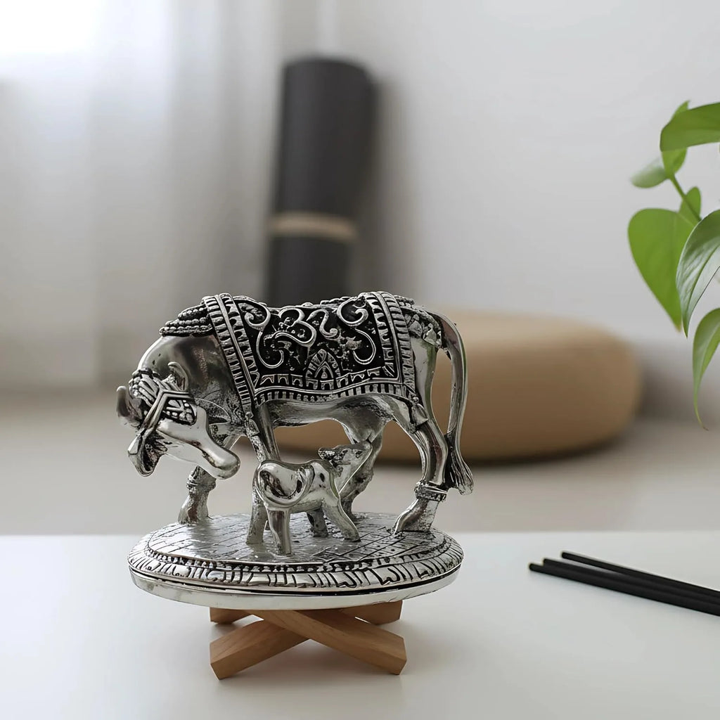 Metal decorative statue of cow and calf with intricate designs on round stand in minimalist room