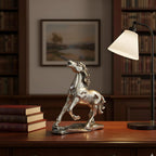 Silver horse sculpture on wooden desk with stacked books and modern table lamp in cozy library