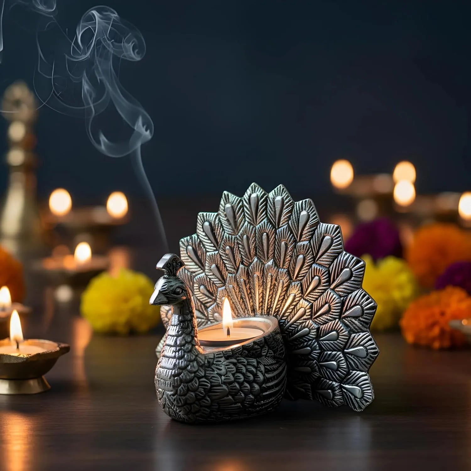 Silver peacock-shaped diya holder with lit tealight candle and smoke, festive floral background