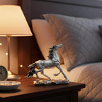 Silver horse statue on a wooden nightstand next to a lit lamp and clock in a cozy bedroom