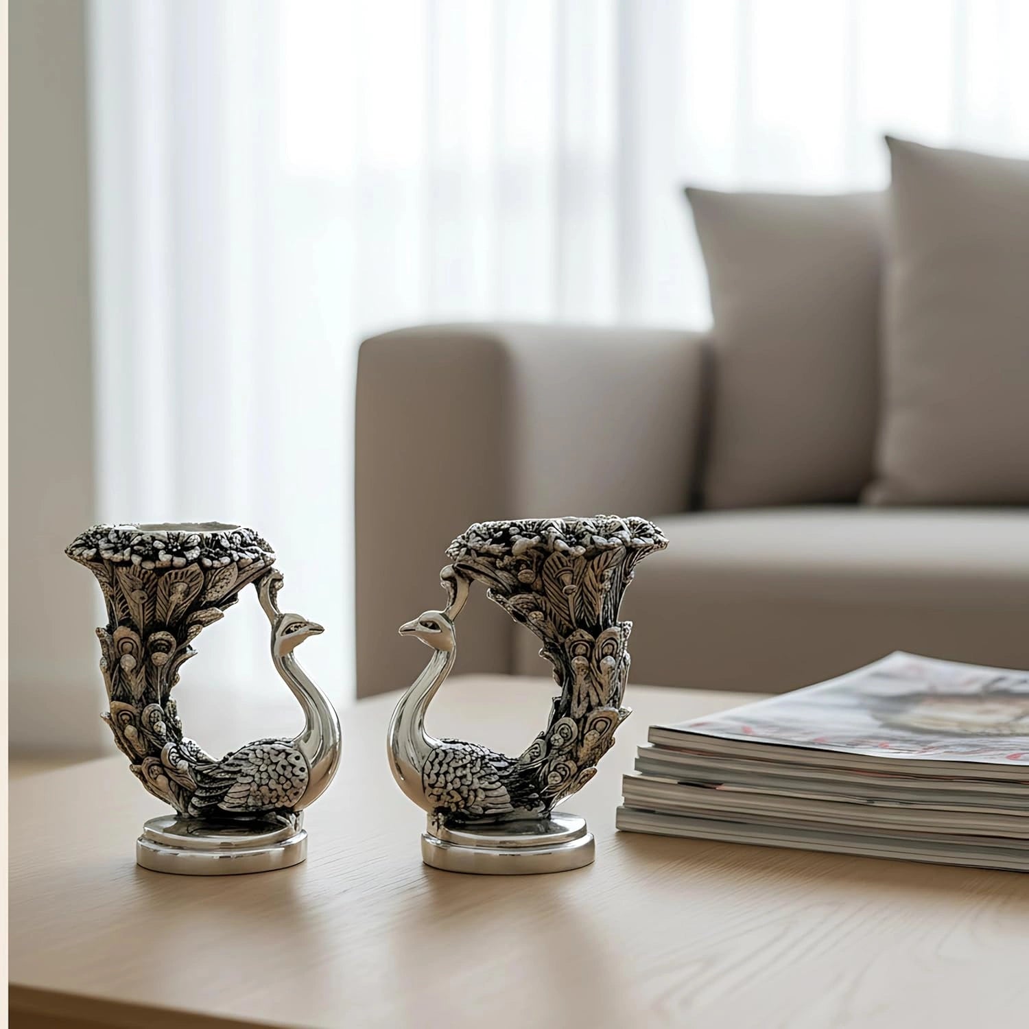 Intricately carved peacock candle holders on wooden coffee table with magazines and blurred sofa background