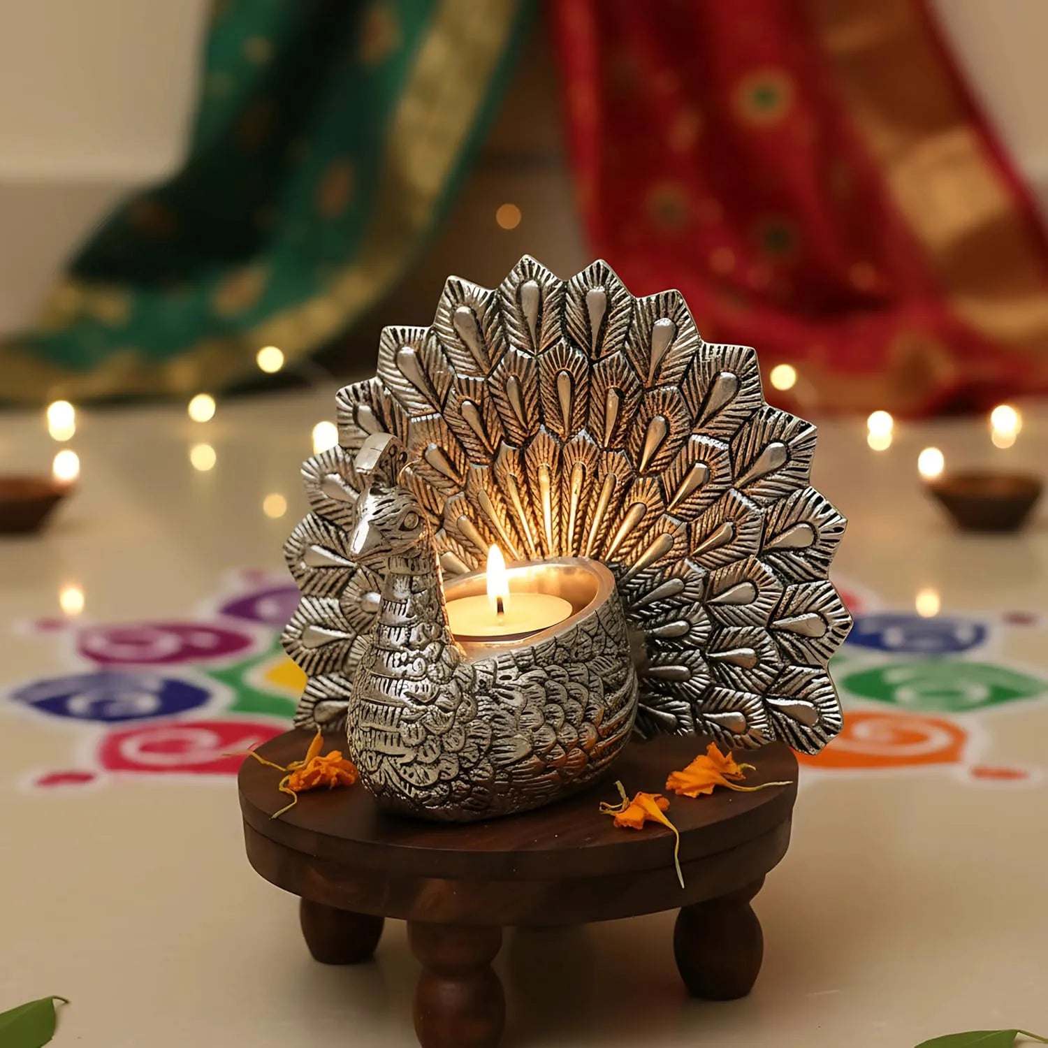 Silver peacock tealight candle holder on wooden stand with festive rangoli and diya lamps background