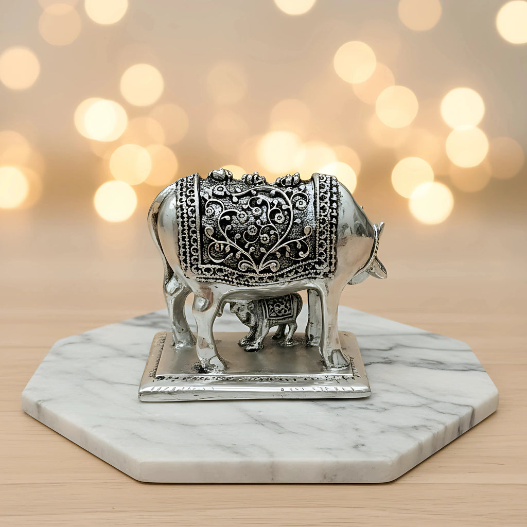 Silver cow and calf figurine with intricate floral engraving on marble hexagonal base