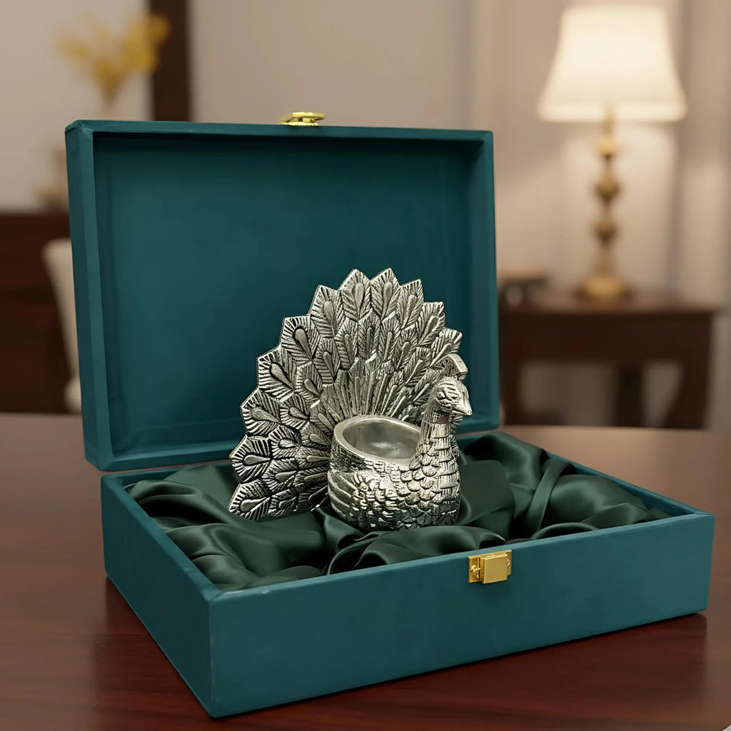 Silver peacock-shaped decorative bowl in green velvet gift box on wooden table
