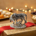 Silver cow and calf statue on gold gift box with red ribbon and festive lights