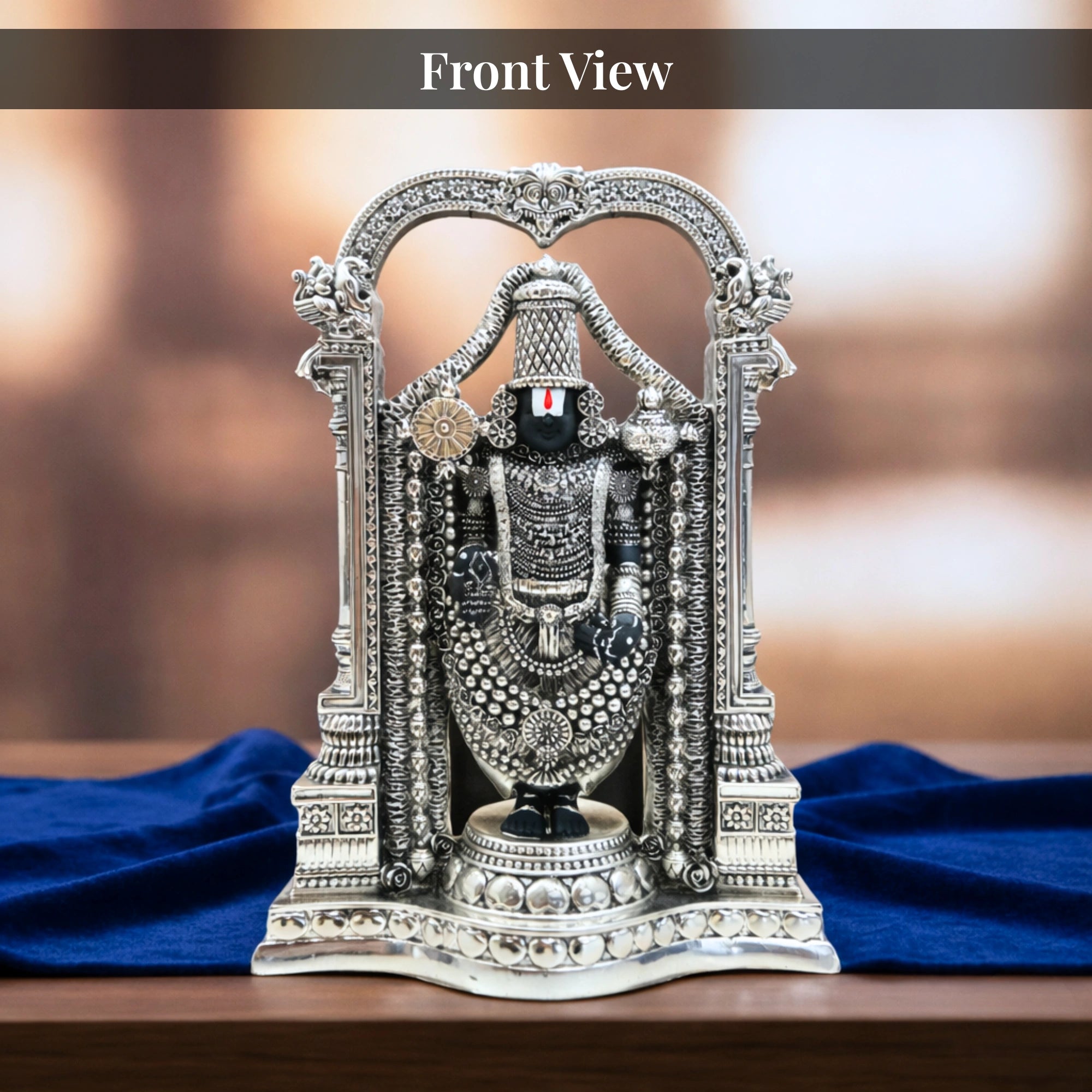 Front view of standing Balaji silver-plated idol with carved arch on royal blue velvet