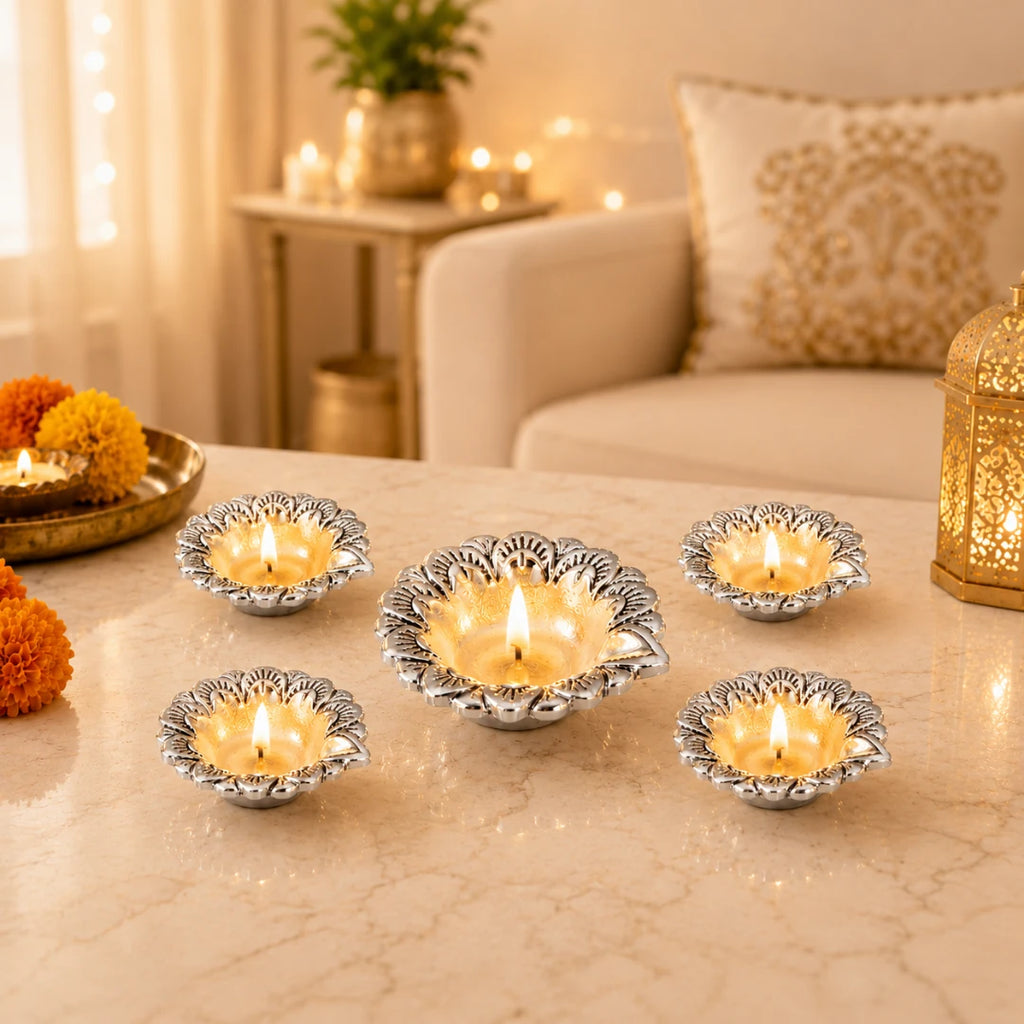 Five lit silver-plated flower diyas on a marble table with marigolds and a gold lantern #set-of-5