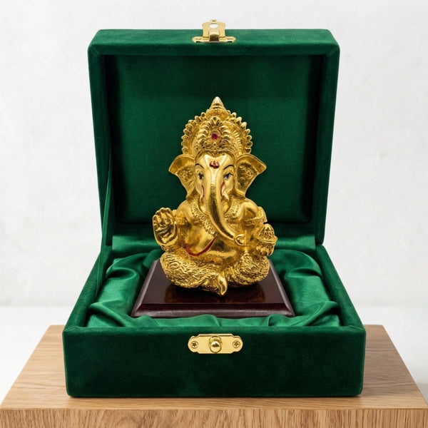 Ganesha gold-plated idol on a wooden base inside a green velvet gift box