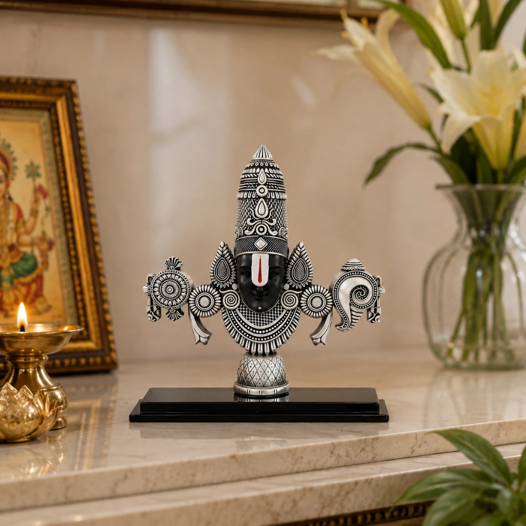 The 6 inch silver Balaji idol on a marble console beside white lilies and a lit brass diya #silver-6-inch
