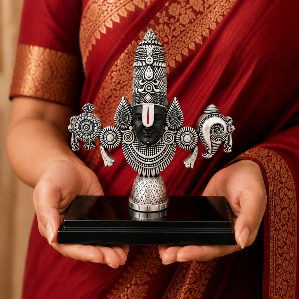 A woman in a red saree holding the 8 inch silver Balaji idol on its black base #silver-8-inch