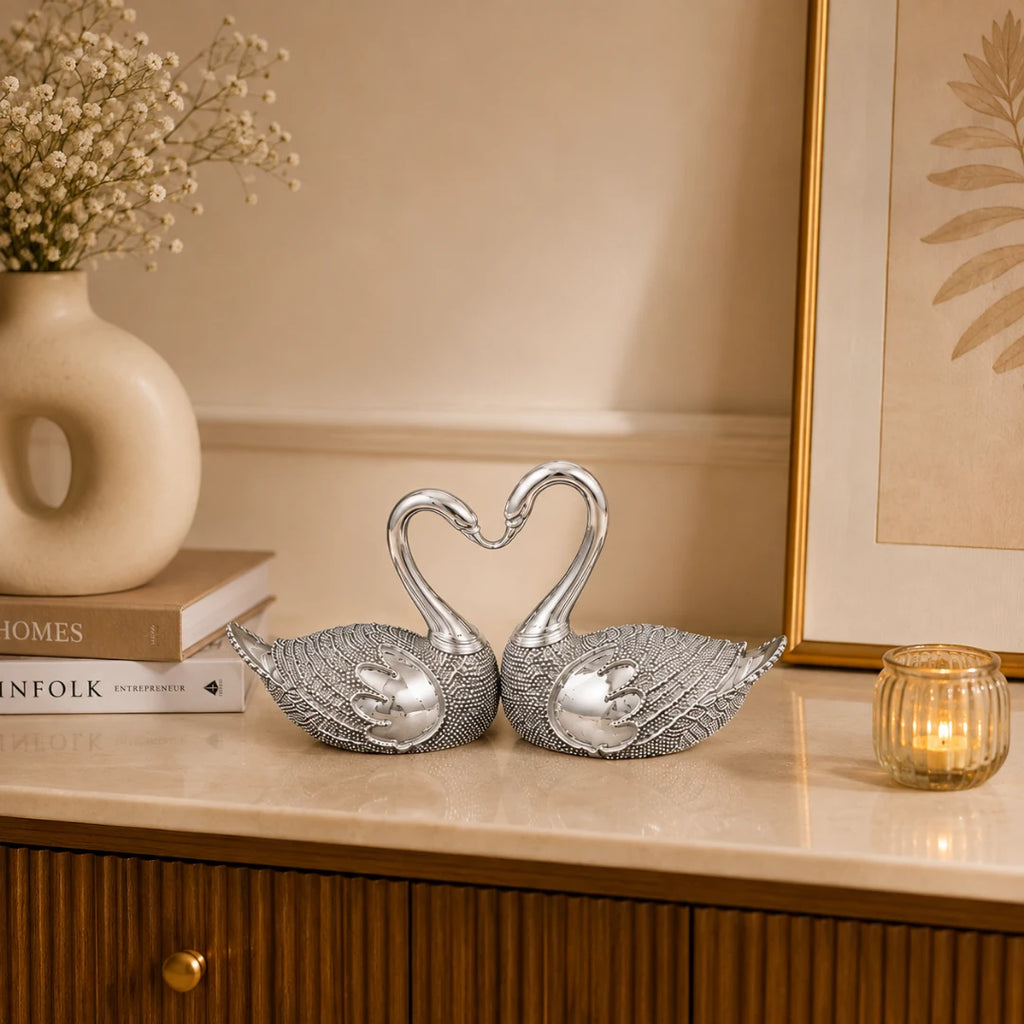 Silver swan pair styled on a marble console with a vase, books and a lit candle #5-inch